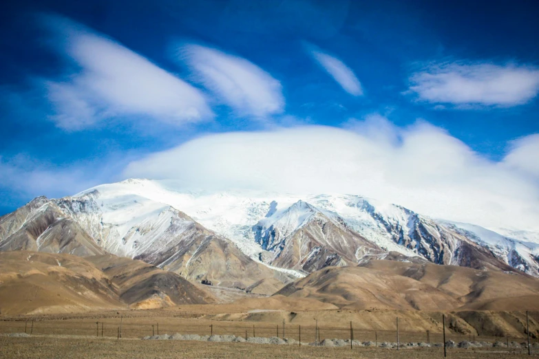 a large mountain covered in snow next to a field, by Muggur, pexels contest winner, hurufiyya, cinematic silk road lanscape, panels, am a naranbaatar ganbold, high resolution