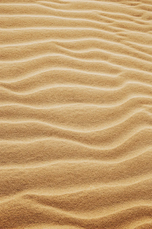 a sandy beach with waves in the sand, an album cover, trending on pexels, symbolism, subtle pattern, light brown, technologies, wrinkles