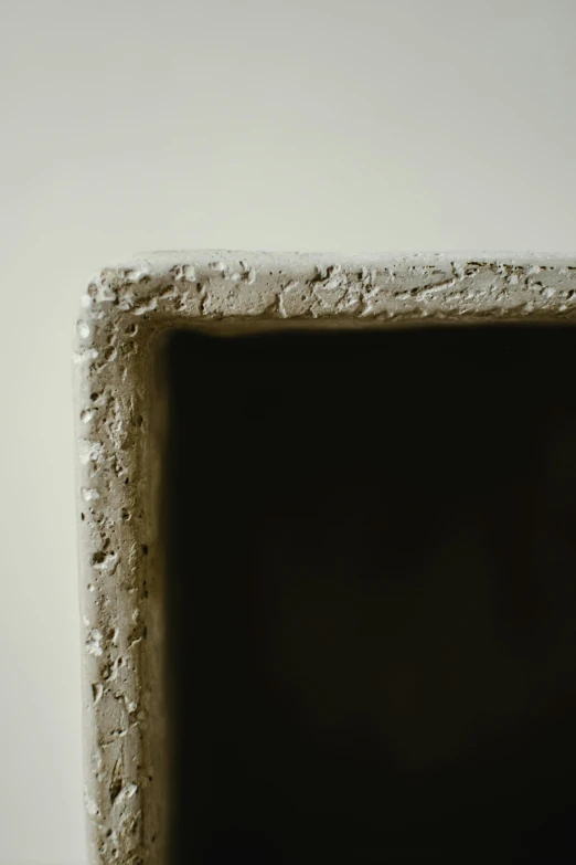 a close up of a square object on a table, inspired by Lucio Fontana, stucco walls, anish kapoor black, zoomed in, medium frame