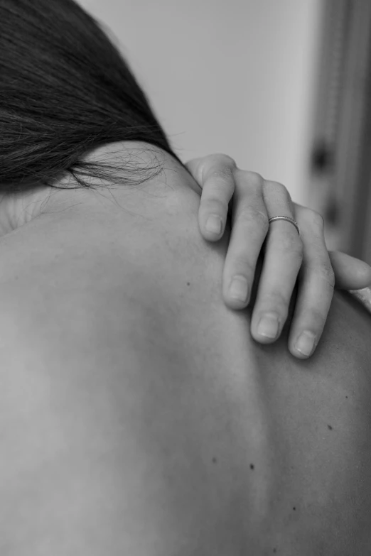 a black and white photo of a woman with her back to the camera, releasing pain, holding an epée, white neck visible, portrait of head and body