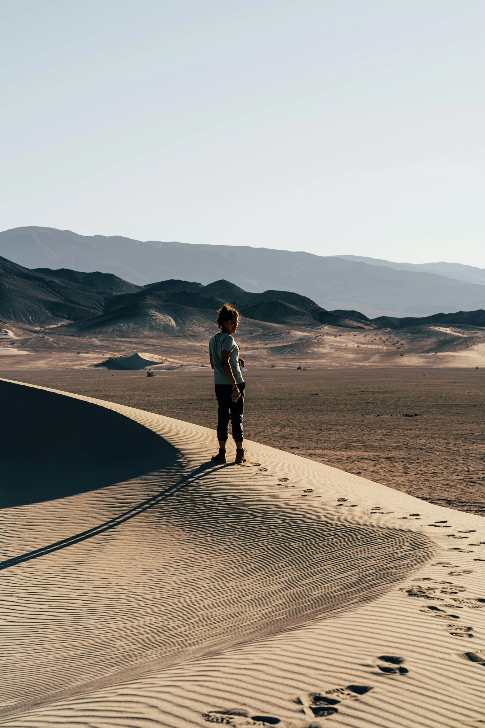 a person standing on top of a sand dune, neil blomkamp film landscape, death valley, gazing off into the horizon, from star wars