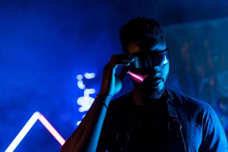 a man holding a cell phone up to his ear, cyberpunk art, by Adam Marczyński, pexels contest winner, afrofuturism, light sabers, unreal engine : : rave makeup, cyber goggles, red and blue black light