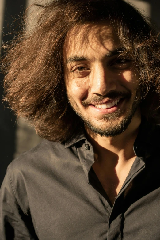 a close up of a person with long hair, an album cover, pexels contest winner, antipodeans, navid negahban, his smile threw shadows, nice afternoon lighting, large messy hair style