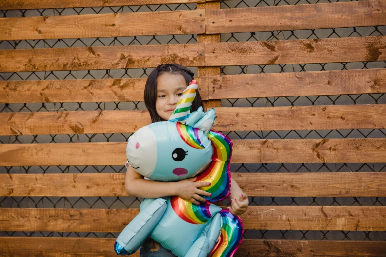 a little girl that is holding a stuffed animal, a cartoon, by Julia Pishtar, pexels contest winner, graffiti, blue unicorn, inflatable, a wooden, glossy surface