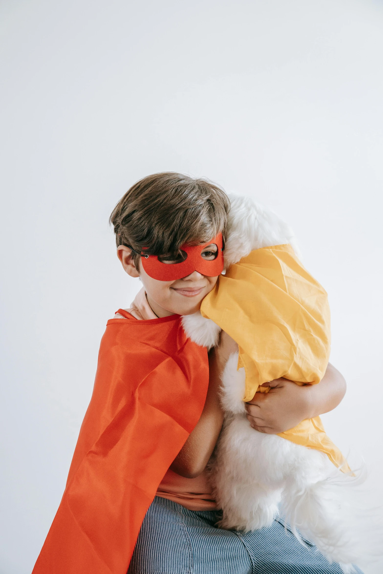 a boy in an orange cape holding a white dog, pexels, hypermodernism, super hero mask, hugging each other, wearing red and yellow hero suit, product shot