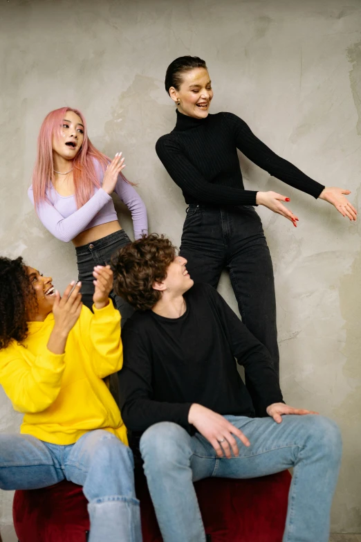 a group of people sitting on top of a red couch, trending on pexels, antipodeans, woman in streetwear, greeting hand on head, pastel clothing, wearing a black sweater