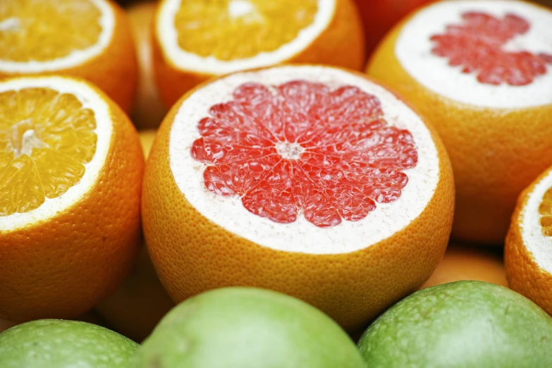 a close up of a bunch of oranges and limes, by Julian Allen, pexels, sliced grapefruit, thumbnail, grainy photo, vibrant red and green colours