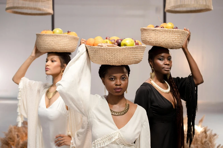 a group of women standing next to each other holding baskets on their heads, trending on unsplash, afrofuturism, fashion show photo, fruit basket, thumbnail, gold and pearl necklaces