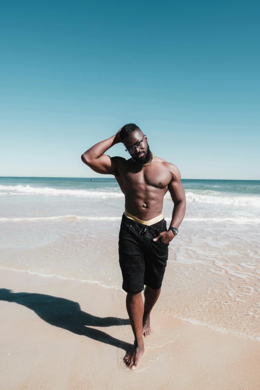 a man standing on top of a beach next to the ocean, man is with black skin, bearded and built, thighs, profile image