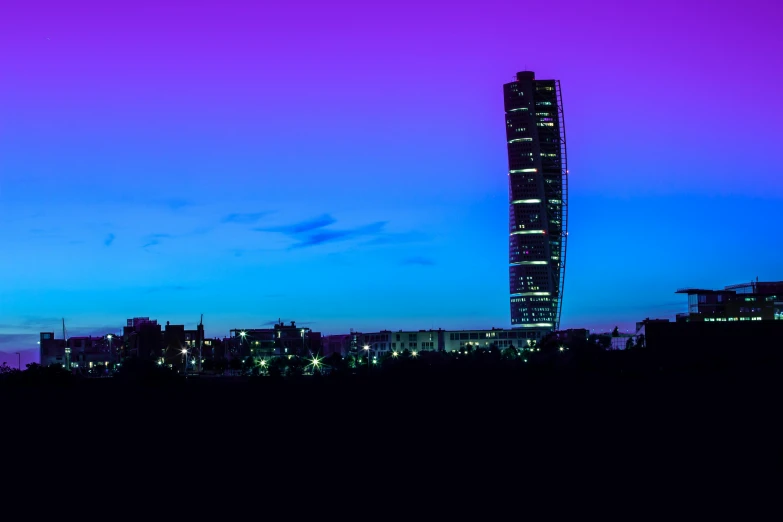 a very tall building sitting in the middle of a city, inspired by Mike "Beeple" Winkelmann, unsplash contest winner, purple and blue colored, capital of estonia, twilight skyline, james turrell building