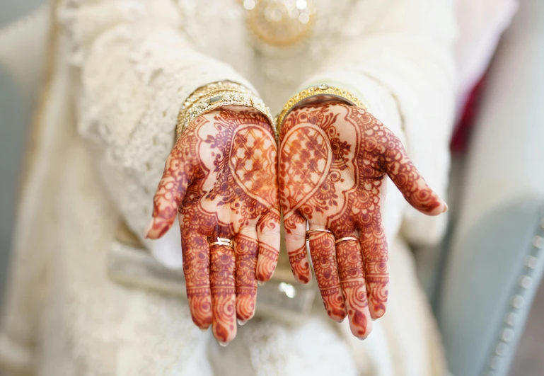 a close up of a person's hands with henna tattoos, an album cover, red white and gold color scheme, several hearts, detailed expression, wedding