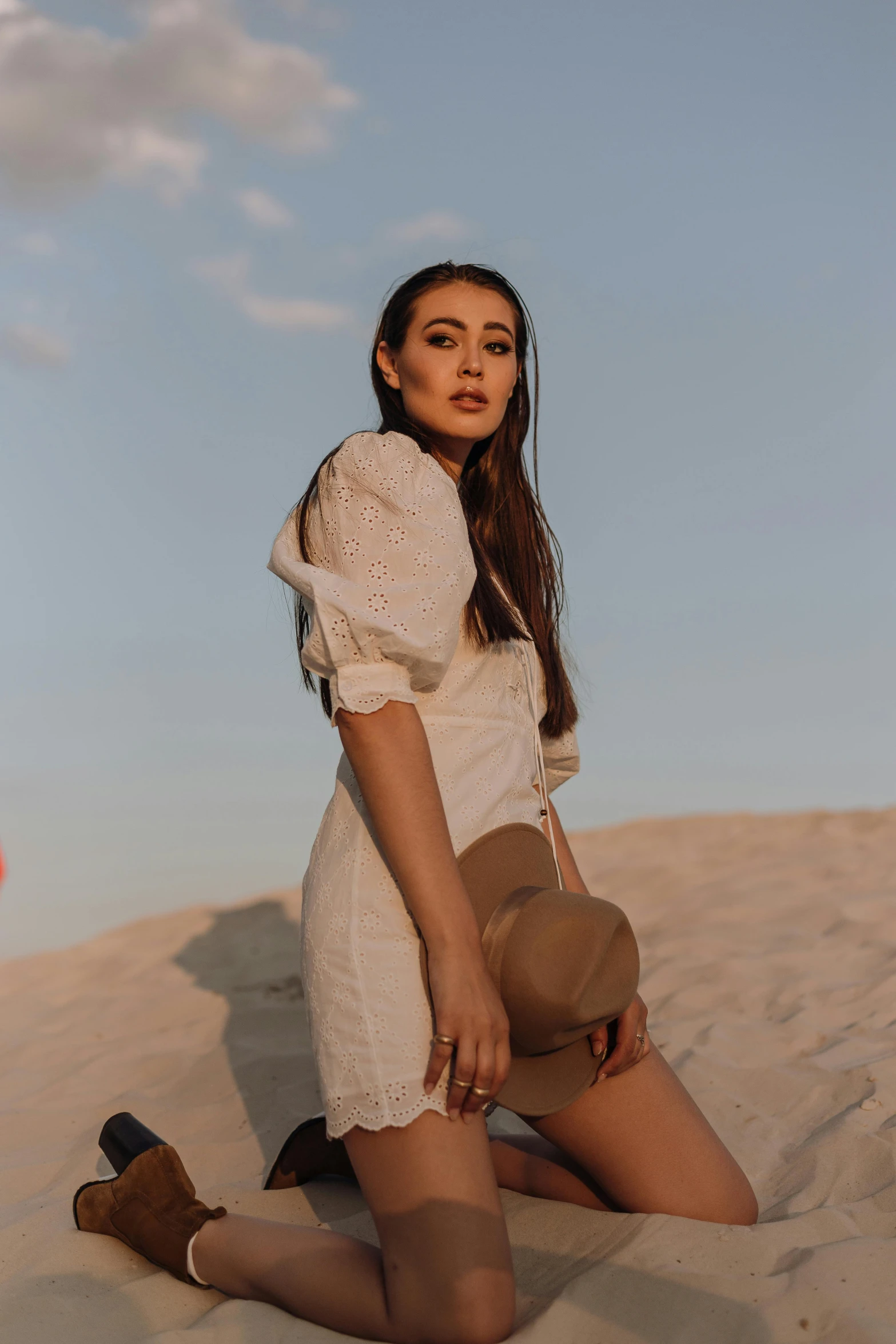 a woman sitting on top of a sand dune, by Robbie Trevino, trending on pexels, madison beer girl portrait, wearing a white dress, puff sleeves, lifestyle