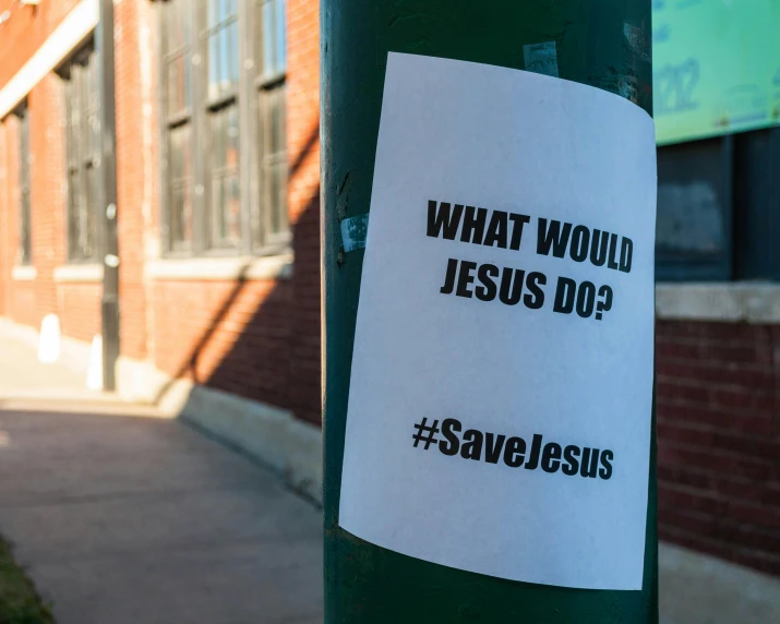 a sticker on a pole that says what would jesus do?, a poster, graffiti, salvation, slide show, crosswalks, press release
