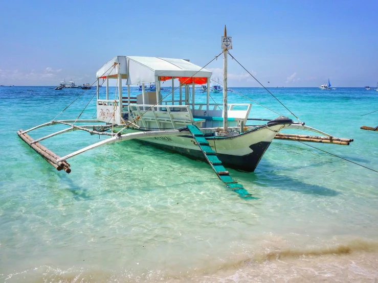 a boat that is sitting in the water, white sand, on a beach