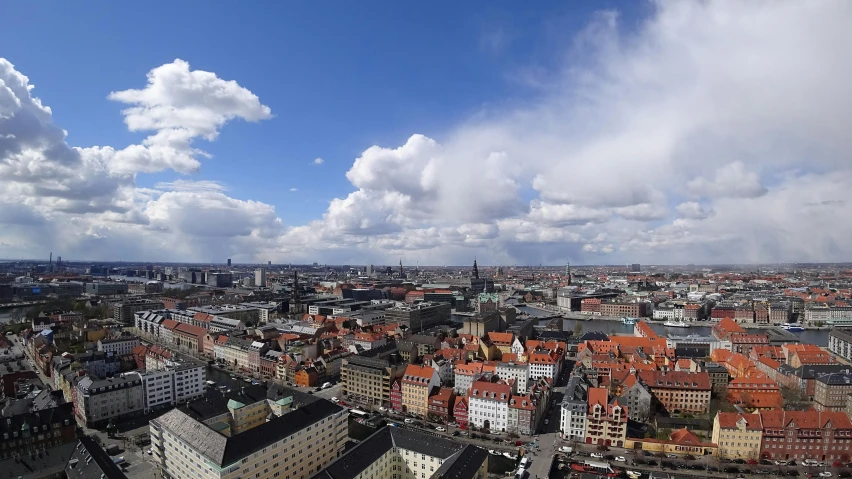 a view of a city from the top of a building, by Tom Wänerstrand, square, blue sky, jörmungandr, low quality photo