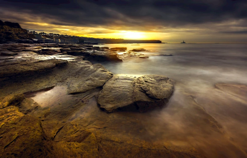 a sunset over the ocean with rocks in the foreground, by Peter Churcher, pexels contest winner, manly, ochre, grey, hd footage