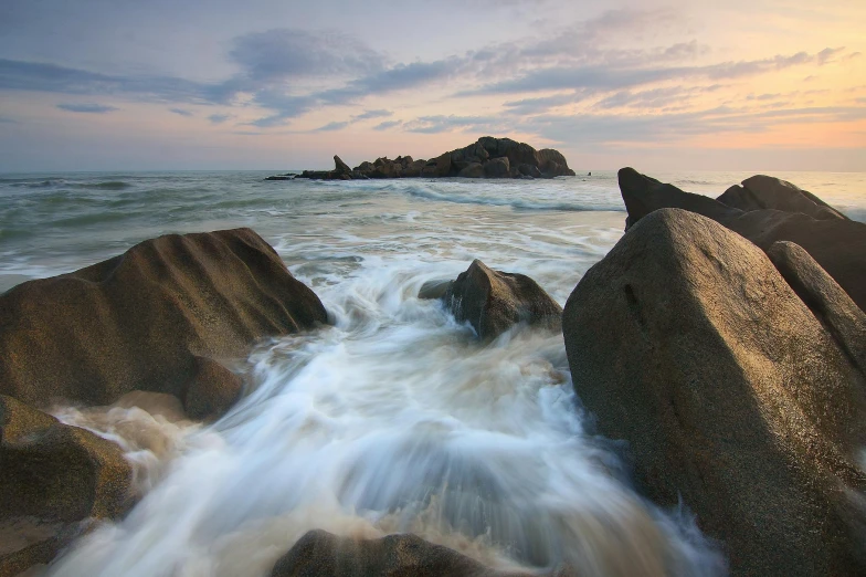 a large body of water sitting on top of a rocky beach, by Reuben Tam, sri lanka, medium format, water swirling, award winning image