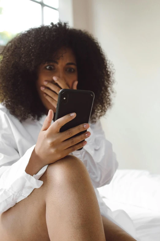 a woman sitting on a bed holding a cell phone, trending on pexels, happening, fleshy creature above her mouth, ashteroth, hiding, snapchat photo