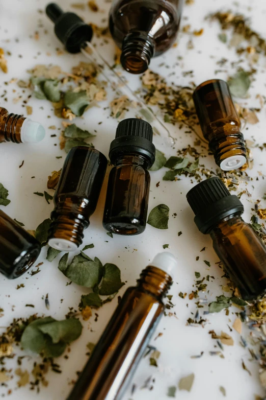 a table topped with bottles filled with different types of essential oils, by Daniel Lieske, trending on pexels, sage smoke, brown, profile image, 1 6 x 1 6