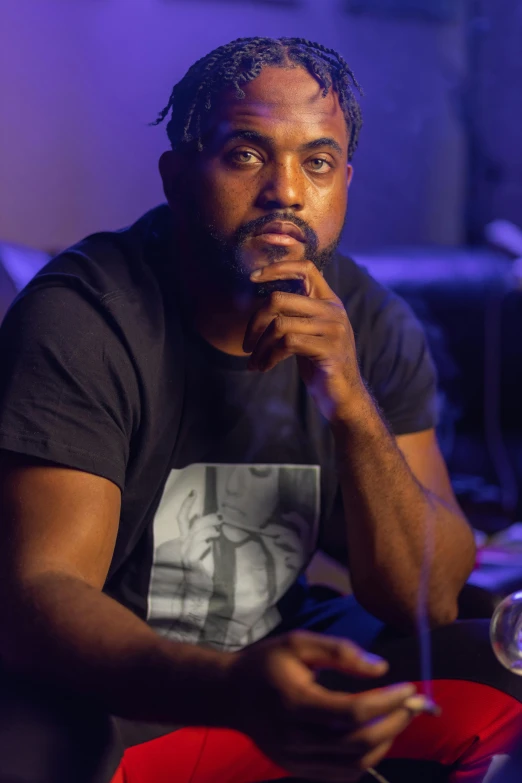 a man sitting on a couch holding a microphone, inspired by Rajmund Kanelba, featured on reddit, black arts movement, sitting at a bar, serious focussed look, closeup portrait shot, kanye