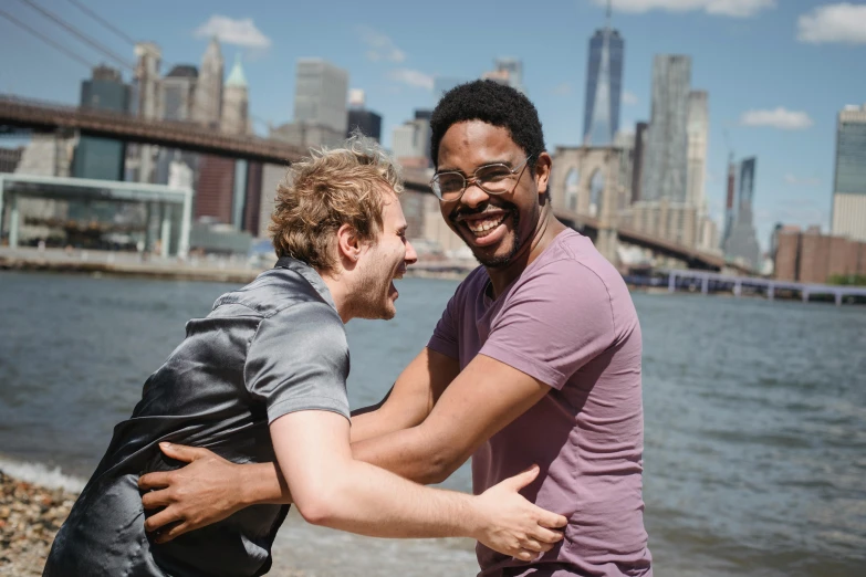 a couple of men standing next to each other on a beach, a photo, happening, brooklyn background, very excited, sirius a and sirius b, embracing