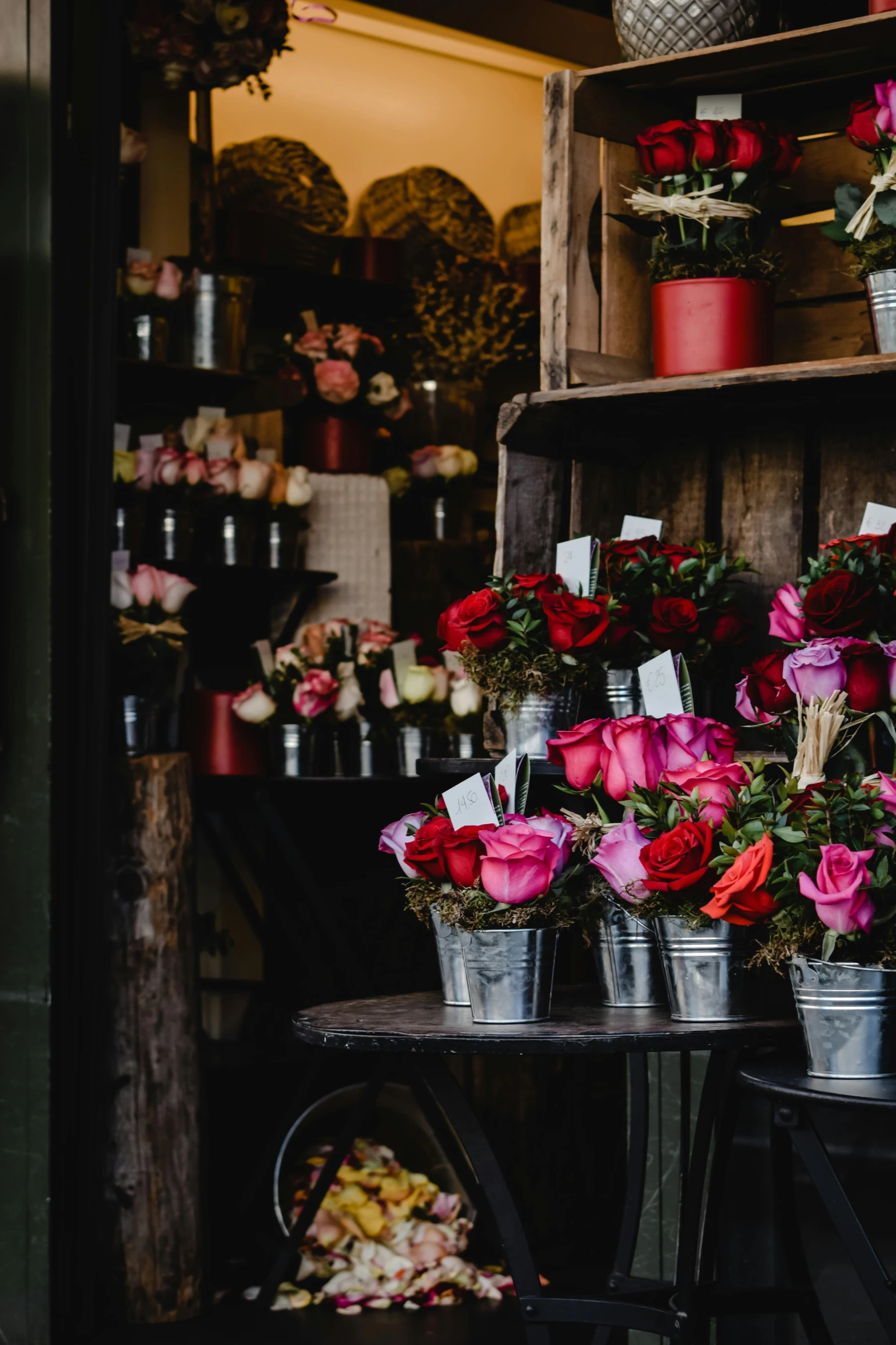 a bunch of buckets of flowers sitting on top of a table, storefront, red roses, bright and moody, pink