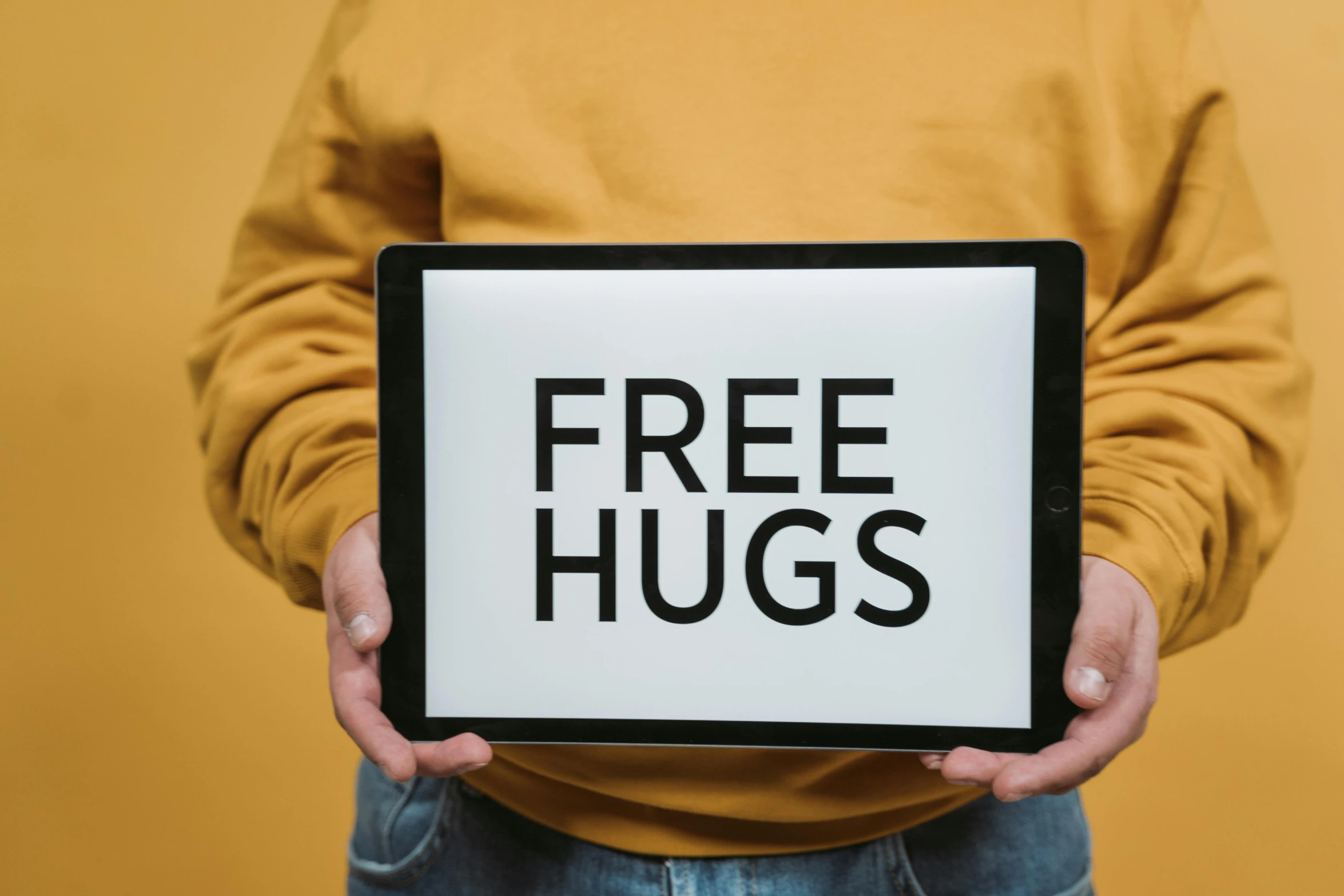 a person holding a tablet with a free hugs sign on it, pexels, hurufiyya, avatar image, corduroy, free, fan favorite