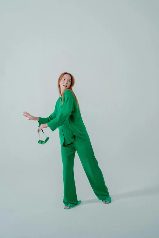 a woman in a green suit holding a pair of scissors, inspired by Eva Gonzalès, trending on pexels, wearing a baggy pajamas, young redhead girl in motion, pose 4 of 1 6, relaxed pose