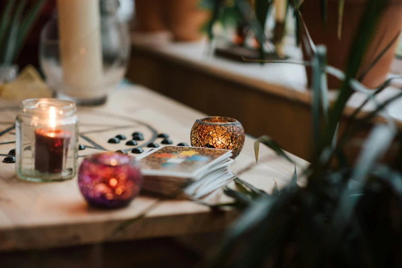 a couple of candles sitting on top of a wooden table, a still life, trending on pexels, arts and crafts movement, lush plants and lanterns, the glass bead game, cosy vibes, magical library bokeh