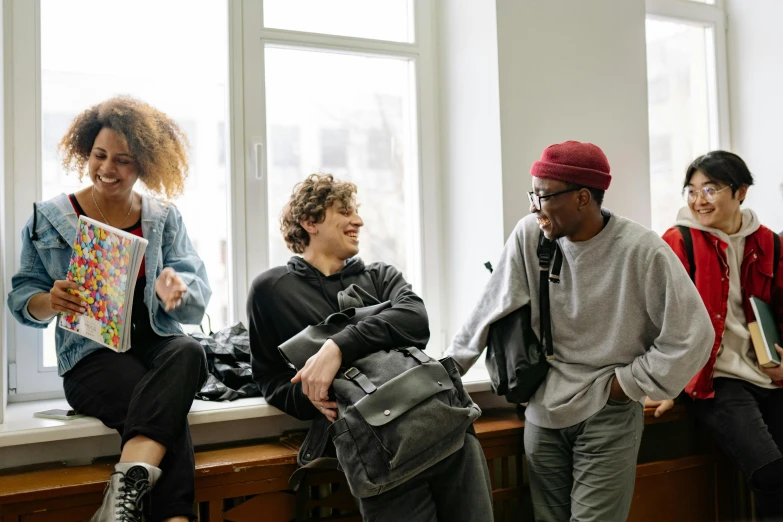 a group of people sitting on a window sill, by Nina Hamnett, trending on pexels, happening, standing in class, laughing menacingly, male teenager, product introduction photo