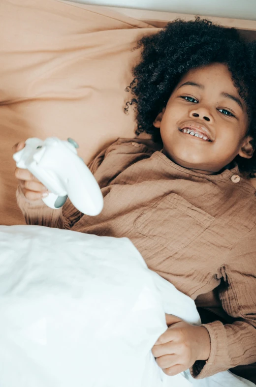 a little girl laying in bed with a remote control, pexels contest winner, happening, diaper disposal robot, holding a white duck, african american girl, caring fatherly wide forehead