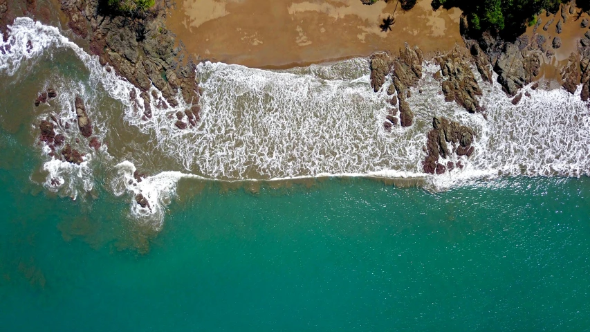 a large body of water next to a sandy beach, by Peter Churcher, pexels contest winner, mid air shot, puerto rico, geology, sparkling cove