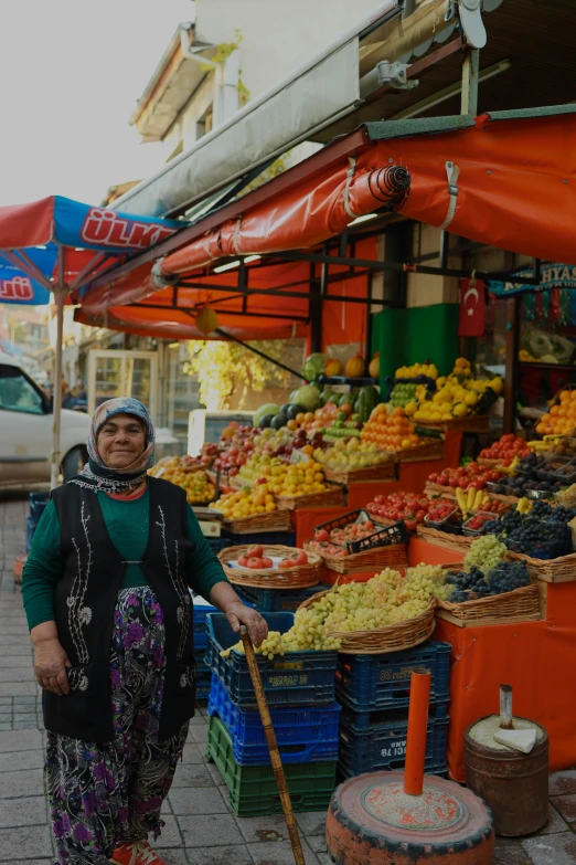a woman standing in front of a fruit stand, istanbul, farmer's market setting, square, trending photo