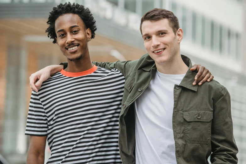 two men standing next to each other in front of a building, pexels contest winner, wearing stripe shirt, diverse ages, best friends, with a white complexion