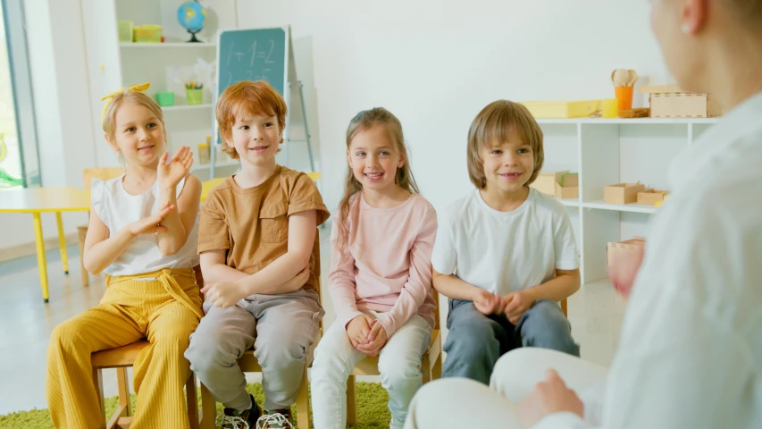 a group of children sitting on chairs in a room