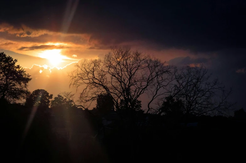 the sun is setting behind some trees, a picture, unsplash, australian tonalism, ominous skies, golden hour photo, ((sunset))