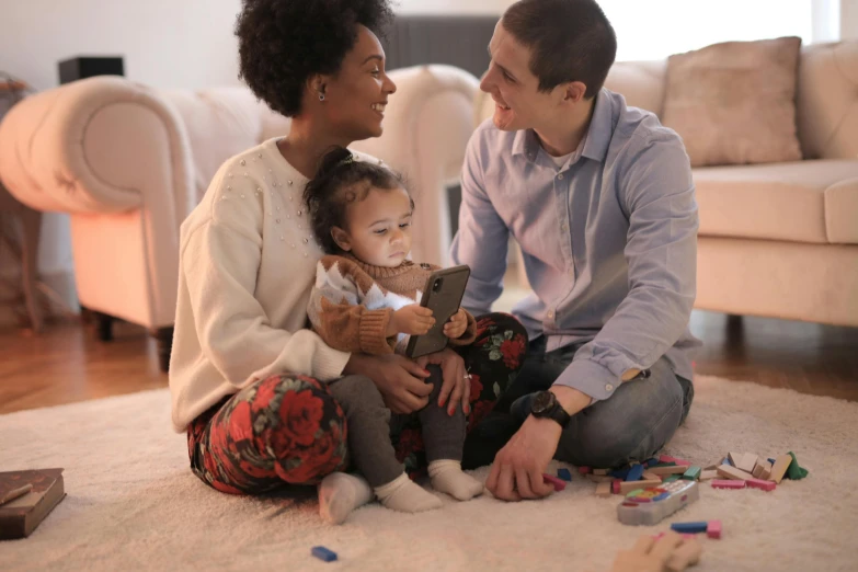 a man and woman sitting on the floor playing with a baby, a cartoon, pexels, figuration libre, light skinned african young girl, rectangle, decoration, small in size