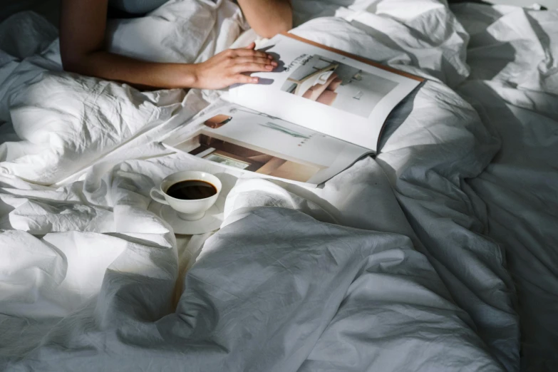 a woman laying in bed reading a book and a cup of coffee, pexels contest winner, happening, white sheets, magazines, julia sarda, gif