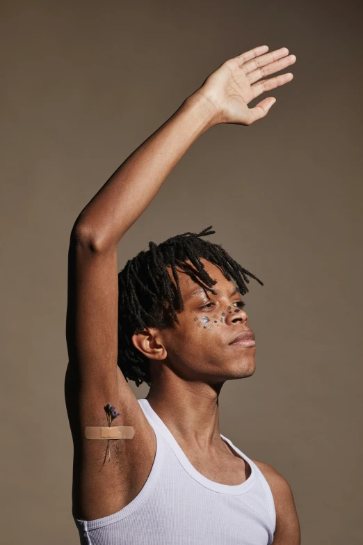 a man with a tattoo on his arm, an album cover, by Lily Delissa Joseph, trending on pexels, black arts movement, delicate androgynous prince, raising an arm, julian ope, dancer