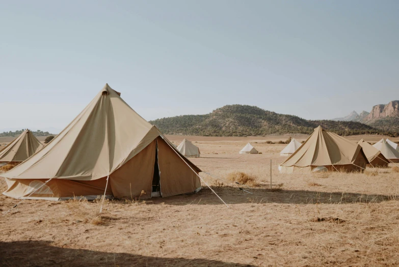 a group of tents sitting in the middle of a desert, ibiza, muted browns, beige, college