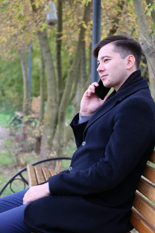 a man sitting on a bench talking on a cell phone, trending on reddit, romanticism, volodymyr zelenskyy, non-binary, profile photo, looking towards camera