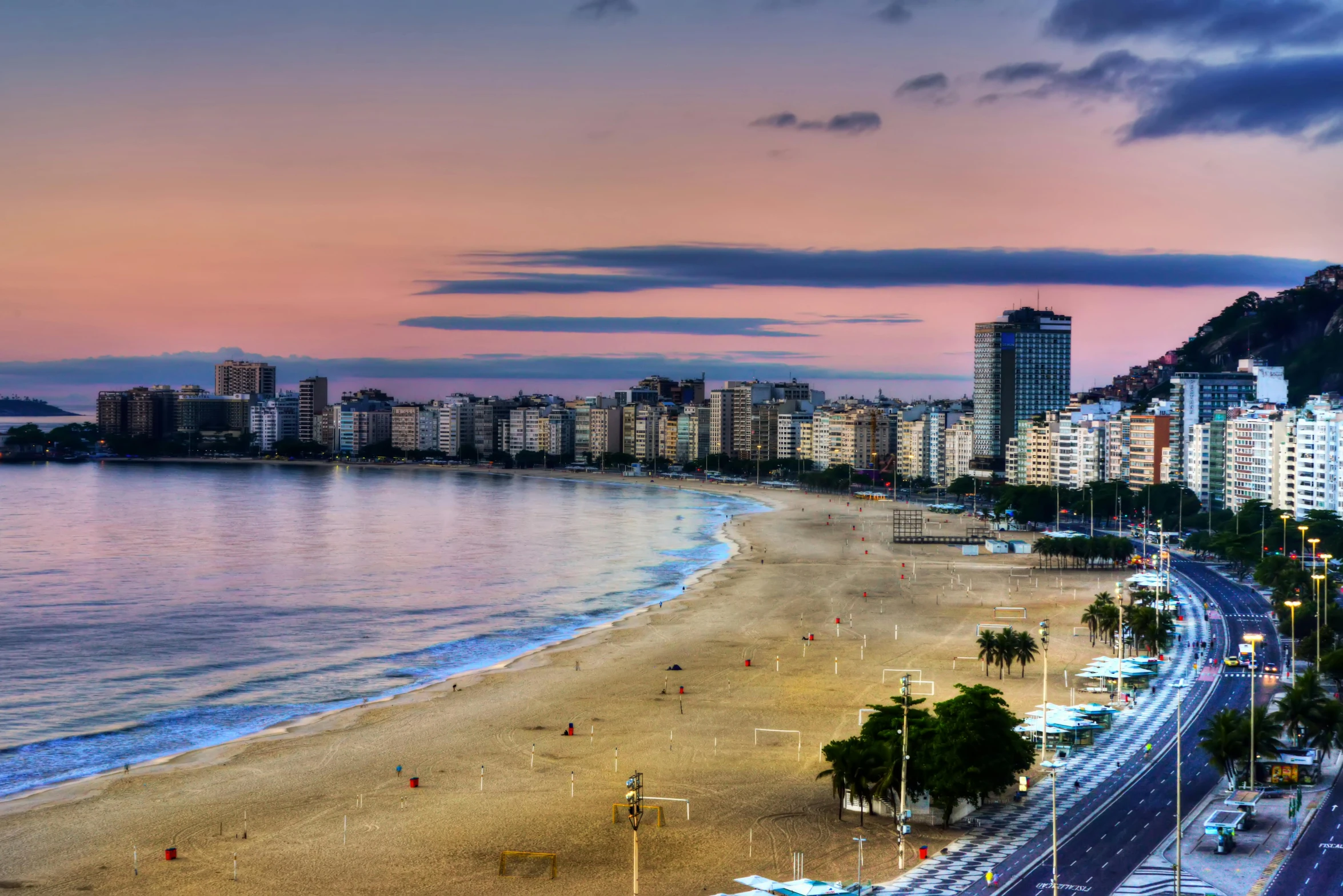 a large body of water next to a sandy beach, a photo, by Felipe Seade, pexels contest winner, vista of a city at sunset, olympics, slide show, thumbnail