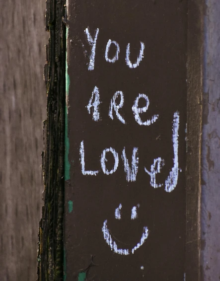 a sign with the words you are loved written on it, chalk art, by Attila Meszlenyi, trending on unsplash, graffiti, lgbt, paul barson, a still of a happy, listing image