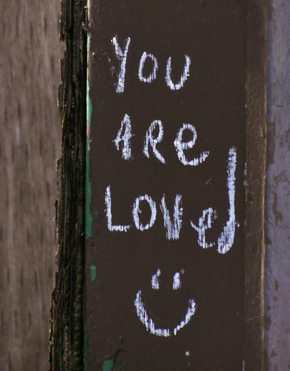 a sign with the words you are loved written on it, chalk art, by Attila Meszlenyi, trending on unsplash, graffiti, lgbt, paul barson, a still of a happy, listing image