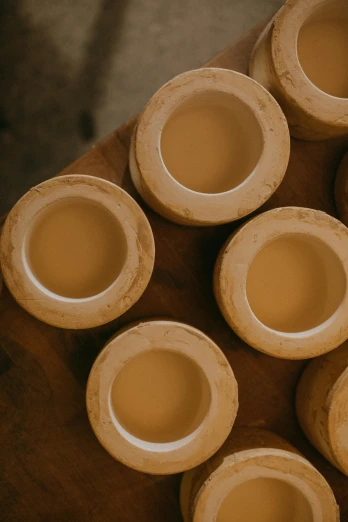 a pile of clay pots sitting on top of a wooden table, circle forms, cream, thumbnail, polished