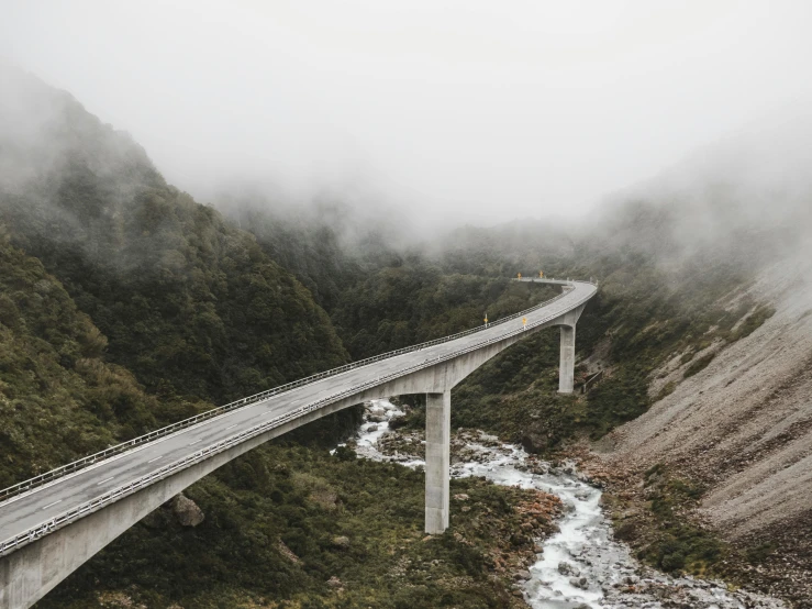 a train traveling over a bridge on a foggy day, unsplash contest winner, new zealand landscape, 2 5 6 x 2 5 6 pixels, paved roads, ignant