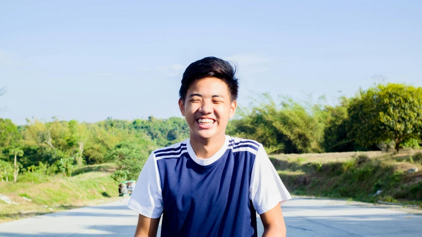 a man riding a skateboard down a street, inspired by Reuben Tam, headshot profile picture, in front of a forest background, smiling slightly, 1 6 years old