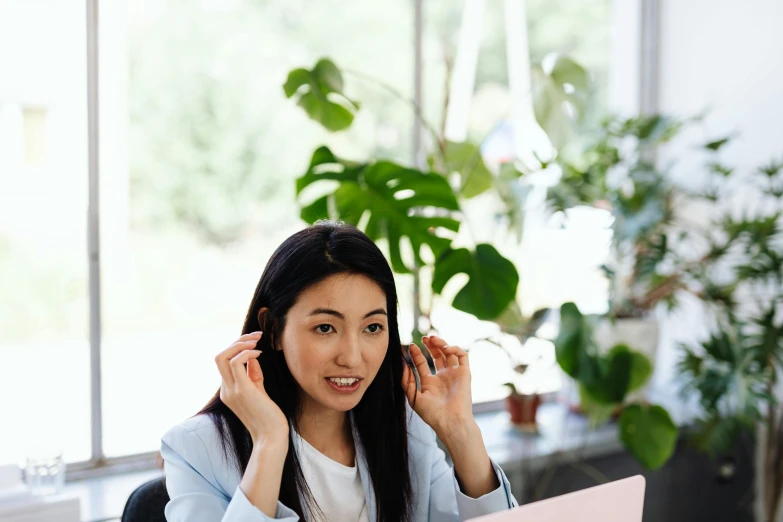 a woman sitting at a table with a laptop in front of her, trending on pexels, hurufiyya, wearing headset, ethnicity : japanese, avatar image, professional image