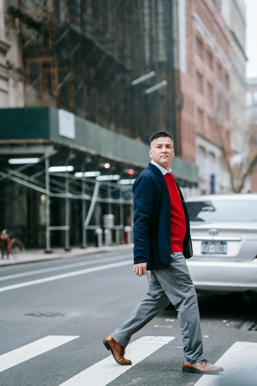 a man crossing the street in front of a car, inspired by Carlos Berlanga, trending on unsplash, renaissance, humans of new york style, red sweater and gray pants, ben shapiro, wearing blue jacket