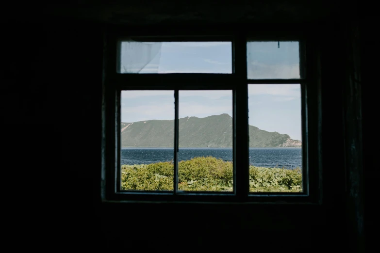 a window with a view of a body of water, unsplash contest winner, hashima island, fan favorite, moody : : wes anderson, light inside the hut